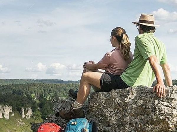 Paar auf einem Felsvorsprung sitzend und in Altmühltal blickend