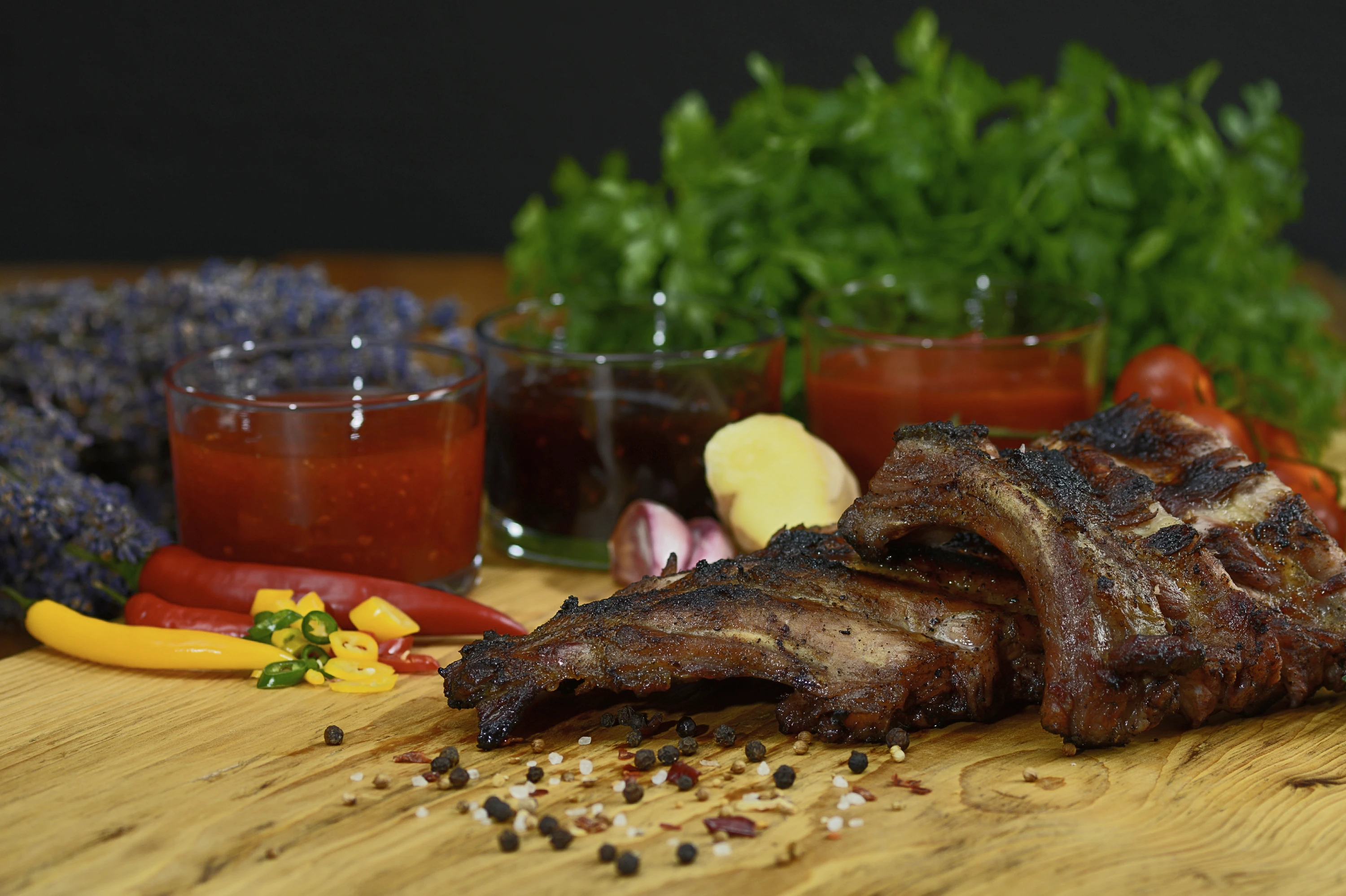 Spareribs, angerichtet mit verschiedenen Dips, Kräutern und Gemüse